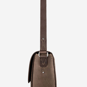 side view of a dark brown leather satchel with stainless steel hardware and hand stitched details