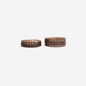 two dark brown leather wristbands, one thick and one thin. Both with detail stitching and the word 'freedom' etched into the leather